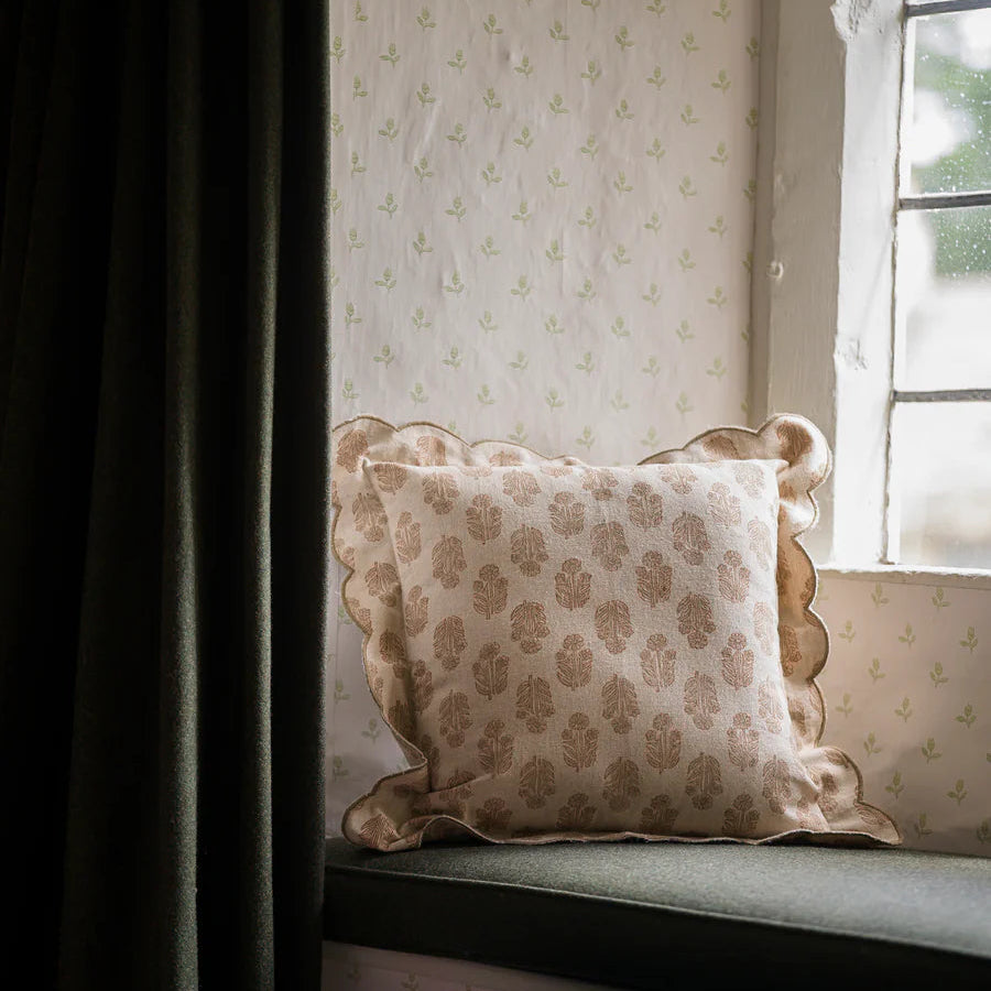 Decorative pillow on a window seat with floral pattern, soft lighting.