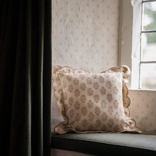 Decorative pillow on a window seat with floral pattern, soft lighting.